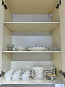 a cabinet filled with white dishes and bowls and plates at Двухэтажный коттедж с 2 апартаментами на озере in Dolinka