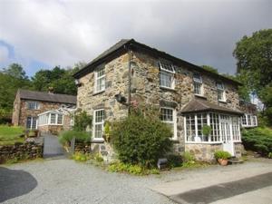 uma antiga casa de pedra com janelas brancas e uma entrada em Sygun Fawr Country House em Beddgelert