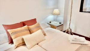 1 dormitorio con 1 cama blanca con almohadas y lámpara en Apartamento Sol, en Gijón