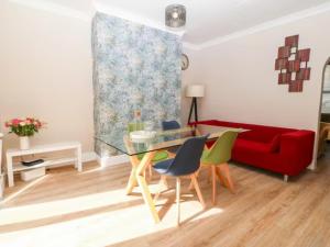 uma sala de estar com uma mesa de vidro e um sofá vermelho em Llandudno 3 Bedroom Holiday Apartment in Town Centre em Llandudno