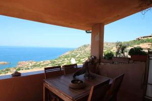 a wooden table on a balcony with a view of the ocean at Belvedere-InfinityHolidays in Costa Paradiso