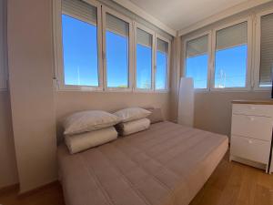 een slaapkamer met 2 kussens op een bed met ramen bij Attic with great terrace close to the sea in El Campello
