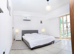een witte slaapkamer met een groot wit bed en ramen bij Private room in shared flat in Nicosia