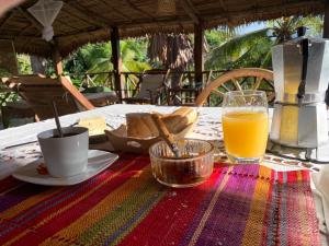 une table avec une assiette de nourriture et un verre de jus d'orange dans l'établissement Les Jardins d'Ankify, à Andimaka