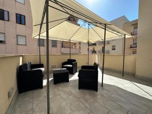un patio con sillas y una sombrilla en un edificio en Dolmen Guest House, en Alghero