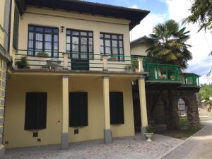 a yellow house with a balcony and a palm tree at Villa Rosi in Cormòns