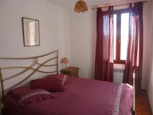 um quarto com uma cama com lençóis roxos e uma janela em les aires em Sainte-Croix-de-Verdon