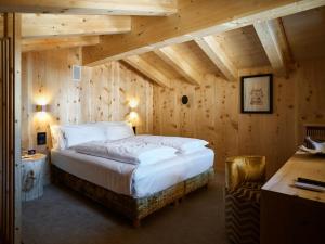a bedroom with a large bed in a room with wooden walls at Dolomiti Lodge Alverà in Cortina dʼAmpezzo