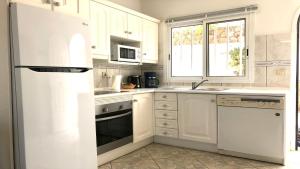 a kitchen with white cabinets and a white refrigerator at Top Seaside Powered by SolymarCalma in Costa Calma
