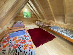 1 dormitorio en el ático con 2 camas y alfombra roja en Wooden houses Bojovic en Gusinje