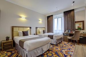 a hotel room with two beds and a desk at Garden Hotel & SPA in Bishkek