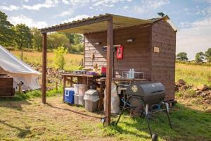 a barbecue and a grill in front of a shed at Roaches Retreat Eco Glampsite - Rocky Reach Bell Tent in Upper Hulme