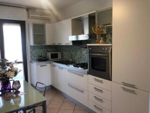 Elmas的住宿－Home Sulcitana，厨房配有白色橱柜和炉灶烤箱。
