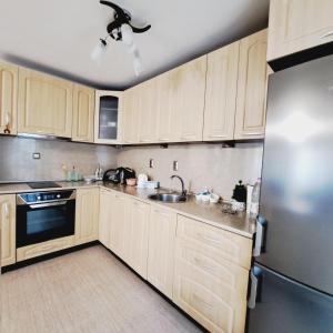 a kitchen with wooden cabinets and a stainless steel refrigerator at Apartment RELAX in the city center, free parking in Yambol