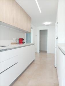 una cocina con encimeras blancas y armarios blancos en Residencial El Trenet 2 B, en Benicàssim