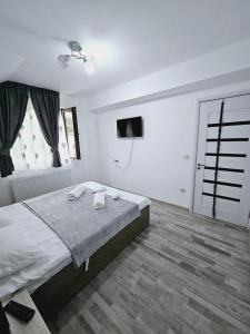 a white bedroom with a bed and a television at Comapart in Bacău