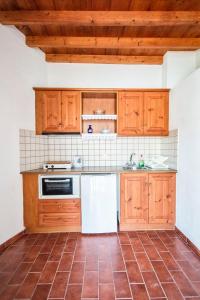 a kitchen with wooden cabinets and a tile floor at Siroco Patmos Agriolivadi in Patmos