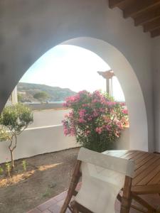 a patio with a table and a bench and flowers at Siroco Patmos Agriolivadi in Patmos
