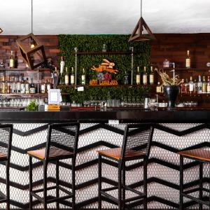 a bar with three chairs and a counter with bottles at Enigmatic Hotel Experience in Cancún