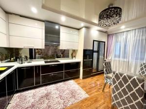a kitchen with black and white cabinets and a rug at Kuat house in Almaty