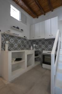 a kitchen with white cabinets and tiles on the wall at Traditional White House in Dhragoulás