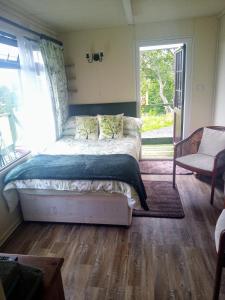 een slaapkamer met een bed en een groot raam bij Peaceful ensuite lakeside cabin 'Tench' in Hadlow Down