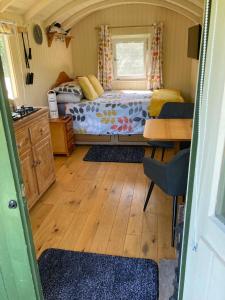 a bedroom with a bed and a desk in a room at Charming tranquil Shepherds Hut with lakeside balcony 'Roach' in Uckfield