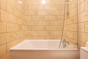 a white bath tub in a bathroom with tiled walls at Beautiful Euston in London