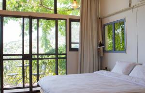 a bedroom with a bed and a large window at Harmony Inn in Safed