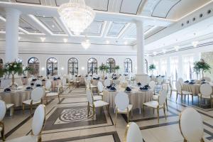 um salão de banquetes com mesas e cadeiras brancas e um lustre em Arkadia Radziejów em Radziejów