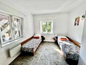 two beds in a room with two windows at Apartman Mirna in Betina