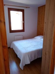 a bedroom with a white bed with a window at La Chamade in Le Biot