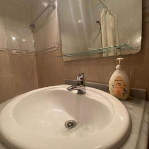 een witte wastafel met een spiegel en een fles zeep bij Apartamento Varanda do Sol in Amora