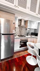 a kitchen with a stainless steel refrigerator and a white chair at Loft de lujo ubicado en zona inmejorable Altamira in Caracas