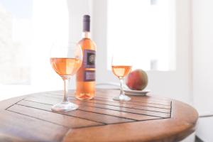 una bottiglia di vino e due bicchieri su un tavolo di legno di Dodomar Selection a Perissa