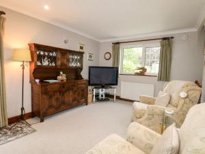 a living room with a couch and a television at Miswells Cottages - Lake View in Turners Hill