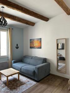 uma sala de estar com um sofá azul e um espelho em Coeur Panier - Charmant T2 entièrement équipé em Marselha
