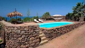 una pared de piedra junto a una piscina en un patio en Dammusi Barone, en Pantelleria