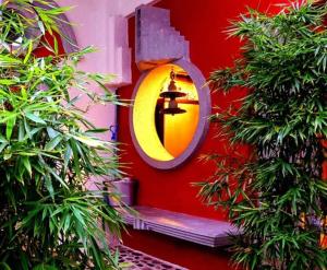 a round mirror on the side of a red wall with a cross at zentral club electrón- jacuzzi. in Belmonte de Miranda