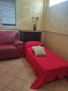 Zimmer mit einem roten Bett und einem Sofa in der Unterkunft Dimora Guaceto in Brindisi