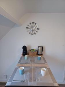 a table with bowls and cups and a clock on the wall at Le Citadin aéroport Beauvais Paris in Beauvais