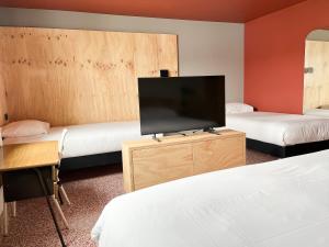a room with two beds and a flat screen tv at Greet hôtel Montpellier Aéroport Parc des Expos in Mauguio