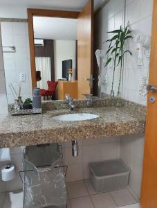 y baño con lavabo y espejo. en Apto no hotel Comfort de Taguatinga, en João Neiva