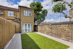 ein Backsteinhaus mit Rasen davor in der Unterkunft London Haven at Rutland House in Ilford