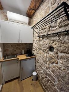 cocina con pared de piedra, fregadero y encimera en Villa Luca, en Grude