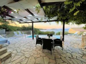 um pátio com uma mesa e cadeiras e uma piscina em Mare Villa Ciel - Private pool - Sea View em Gaios