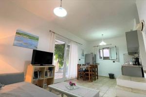 uma sala de estar com um sofá, uma televisão e uma mesa em Mare Villa Ciel - Private pool - Sea View em Gaios