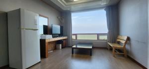 a room with a refrigerator and a desk and a window at Namhae Beach Hotel in Namhae