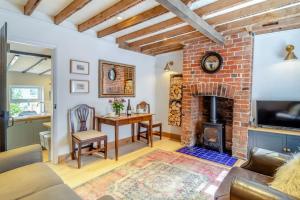- un salon avec une cheminée en briques et une table dans l'établissement Curlew Cottage Woodbridge Suffolk Cosy Victorian cottage for couple and dog, à Woodbridge