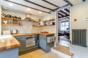 une cuisine avec des placards bleus et un comptoir dans l'établissement Curlew Cottage Woodbridge Suffolk Cosy Victorian cottage for couple and dog, à Woodbridge